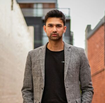 man in gray suit jacket and black pants standing on brown concrete pathway during daytime