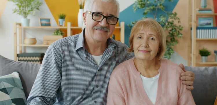 Elderly couple smiling while sitting on a couch.